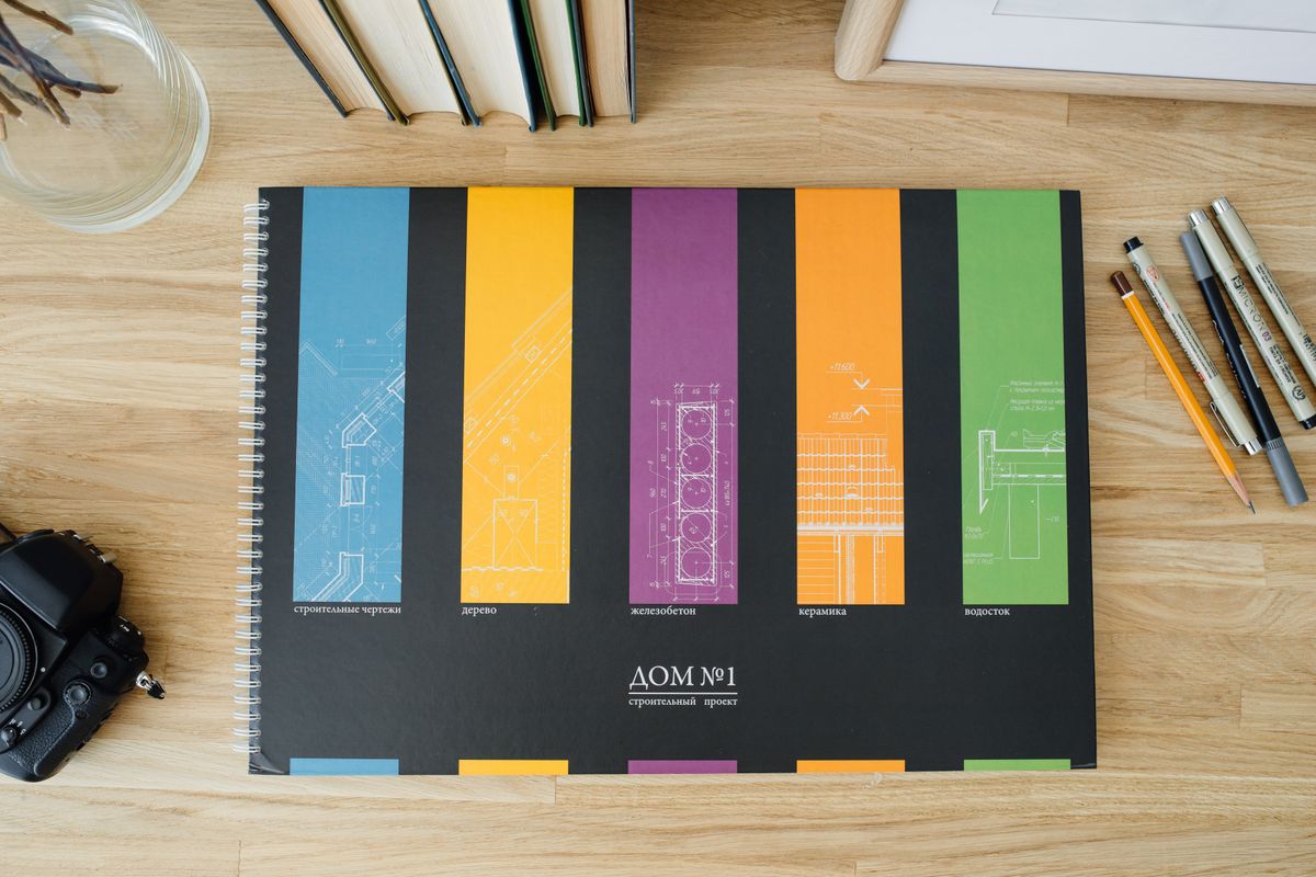 Design and architecture workbook with colorful blueprints on a wooden desk. - Photo by Ivan S on Pexels