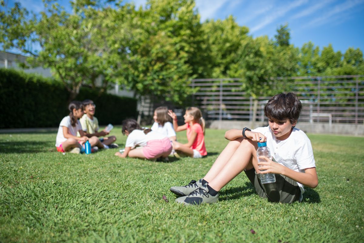 Eine Gruppe von Kindern entspannt und spielt auf dem Rasen in einem sonnigen Park und genießt die Natur. - Foto von Kampus Production auf Pexels