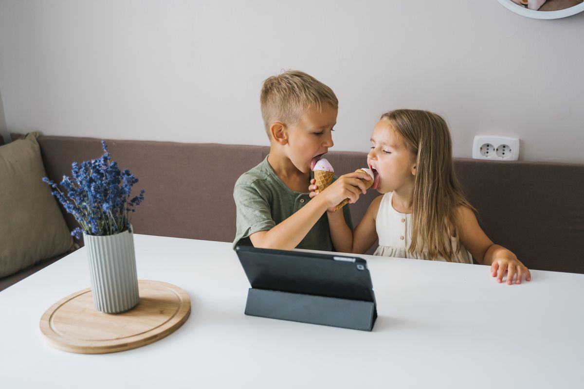 Two kids happily sharing an ice cream cone in a cozy indoor setting. - Photo by Tima Miroshnichenko on Pexels