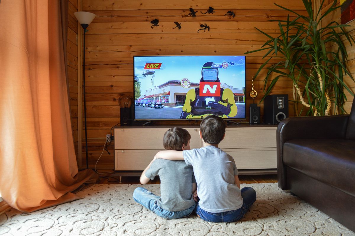 Back view of unrecognizable little children in similar casual outfits resting on floor at home and hugging while watching cartoon on TV - Photo by Vika Glitter on Pexels