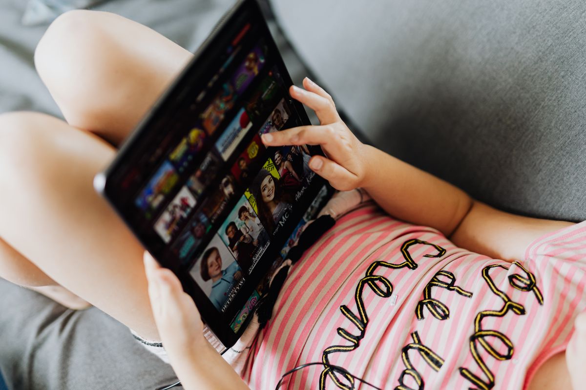 Young girl lying down using a tablet for entertainment and learning indoors. - Photo by www.kaboompics.com on Pexels