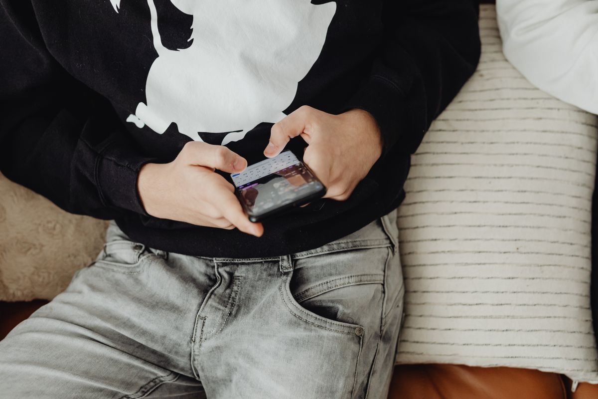 Close-up of a teenager sitting and using a smartphone on a comfortable sofa. - Photo by www.kaboompics.com on Pexels