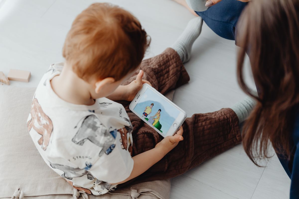 A child sits on the floor using a tablet to watch a colorful cartoon indoors. - Photo by www.kaboompics.com on Pexels